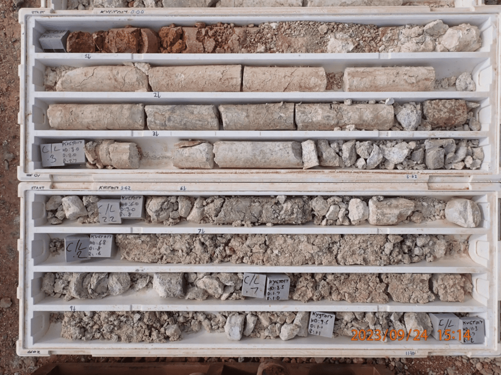 Image of geological core samples arranged in two trays, each containing several segments of rock samples of varying colors and textures. Labels with numbers and dates are visible. The date "2023/09/24 15:18" is marked on the photo.